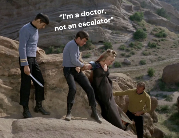 A screenshot from the original Star Trek series episode "Friday's Child" in which Dr. McCoy assists a woman who is ascending a steep rock face. Spock stands unhelpfully behind the doctor, holding a blade. Captain Kirk, also holding a blade, ascends just below the woman. The caption above Dr. McCoy's head reads: "I'm a doctor, not an escalator".